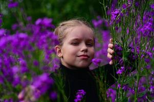 A girl with long hair, walking in the field. A lot of purple flowers Ivan tea. Photo shoot in nature