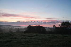 Sunrise over a neighboring forest with meadow in the foreground. Pasture landscape photo