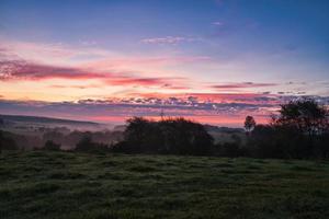 amanecer terminado un vecino bosque con prado en el primer plano. pasto paisaje foto