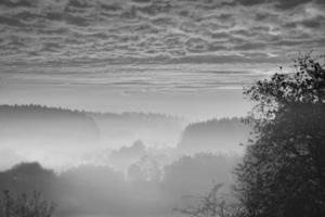 Sunrise over a misty forest. Dawn in fairy forest with dramatic glowing sky photo