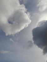 Beautiful black and white clouds on deep blue sky background. Large bright soft fluffy clouds are cover the entire blue sky. photo