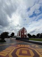 Mataram, Indonesia, February 16, 2023. A gate with the shape of a white traditional house roof and a red cloth motif in Sangkareang Park in the center of Mataram city photo