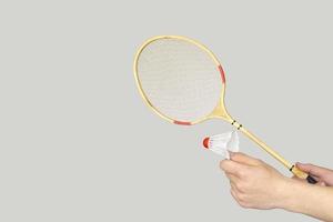 man's hand holding a badminton racket on grey background. photo