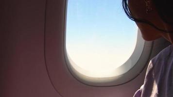 donna sembra su il finestra di un volante aereo. giovane caucasico contento viaggiatori siamo in viaggio di aereo, Guardando il cielo a partire dal sopra e hold passaporto video