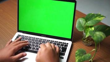 Hand typing on laptop with green screen for mockup on clean wooden desk video