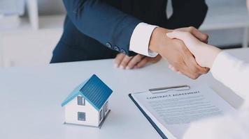 Immobilienmakler-Agent präsentiert und berät den Kunden bei der Entscheidungsfindung, unterzeichnet einen Versicherungsvertrag, kauft und verkauft ein Hausmodell, ein Hypothekendarlehensangebot für und eine Hausversicherung video