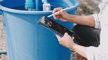 asiatique Oman agriculteur à la recherche biologique des légumes et en portant tablette, portable pour vérification ordres ou qualité ferme dans Matin lumière video