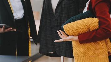 moda progettista l giovane asiatico donna Lavorando utilizzando computer portatile, tavoletta e sorridente mentre in piedi nel laboratorio rispondere su attività commerciale video