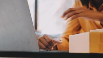 moda desenhador eu jovem ásia mulher trabalhando usando computador portátil, tábua e sorridente enquanto em pé dentro oficina respondendo em o negócio video