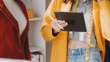 Diverse female fashion designers at work with tailor centimeters on necks and holds tablet and laptop. independent creative design business. video