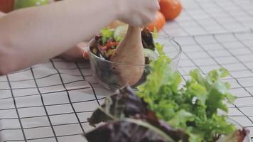 Young and happy woman eating healthy salad sitting on the table with green fresh ingredients indoors video