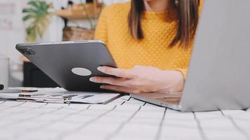 Aziatisch bedrijf vrouw gebruik makend van rekenmachine en laptop voor aan het doen wiskunde financiën Aan een kantoor bureau, belasting, rapport, boekhouding, statistieken, en analytisch Onderzoek concept video