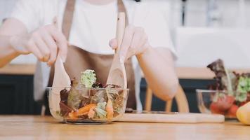 giovane e contento donna mangiare salutare insalata seduta su il tavolo con verde fresco ingredienti in casa video