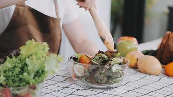 jong en gelukkig vrouw aan het eten gezond salade zittend Aan de tafel met groen vers ingrediënten binnenshuis video