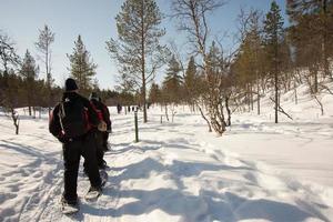 Unrecognizable group of people walking in a row with snow rackets. photo