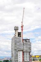 Hoisting cranes working building construction on bright blue sky and big cloud background. photo