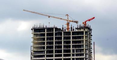 levantamiento grua trabajando edificio construcción en el grande lluvia nubes foto