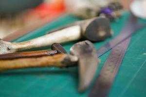 Closeup and crop tools and equipment for leather making with the special hammer made from ox horns. photo