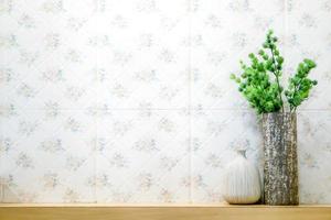 Green plant in different vases put on wooden shelf front of flowers pattern tile in the toilet. photo