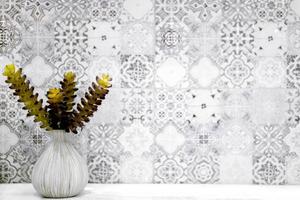 Ornamental plants in small white vase put on white table front of gray pattern tile in the toilet. photo