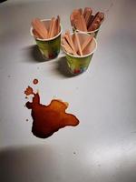 papel tazas de café en un pequeño mesa con un recién derramado café manchar durante un desayuno a el café foto