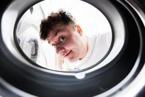 Man view from washing machine inside. Male does laundry daily routine. photo