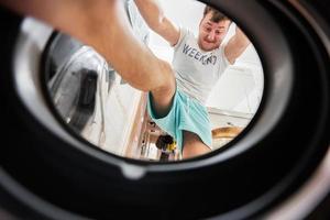 Man view from washing machine inside. Male does daily routine.  Climbs inside, pushing and pressing the laundry with his feet. photo