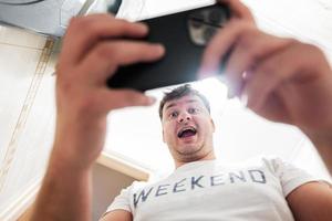 Man with a surprised and happy face looks at the phone screen. photo