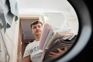 Man view from washing machine inside. Male does laundry daily routine. photo