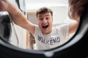 Man view from washing machine inside. Male does laundry daily routine. Funny comedian face. photo