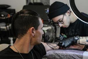 profesional tatuaje artista telas un tatuaje en el del hombre mano. tatuaje artista a trabajar. tatuaje creación proceso. Arte y creatividad foto