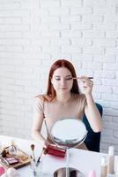 young woman making up at home, using eyeshadows photo