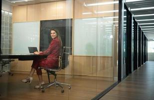 Business woman in red dress in the company's large conference room which is lined with small meeting rooms along the corridor photo