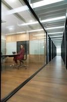 Business woman in red dress in the company's large conference room which is lined with small meeting rooms along the corridor photo