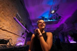Beautiful female DJ dancing to techno in a small club photo
