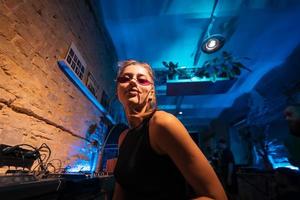 Beautiful female DJ dancing to techno in a small club photo