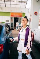 mujer llenando su auto con combustible en una gasolinera foto