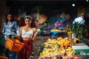 young woman do shopping in supermarket. choosing apples in store photo