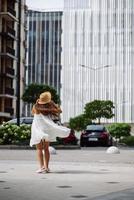 Beautiful pretty woman in white dress walking at city street photo