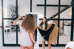 Two women choose and try on clothes at home photo