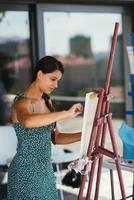 Young woman artist paints with a spatula on the canvas photo