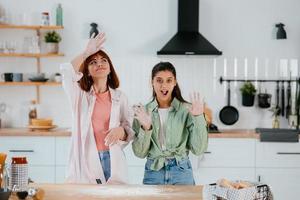 dos hermosas mujeres juegan con harina en la cocina foto