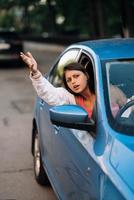 una joven enojada se asoma por la ventana del auto foto