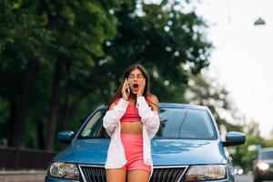 Woman talking on phone near car at the street photo