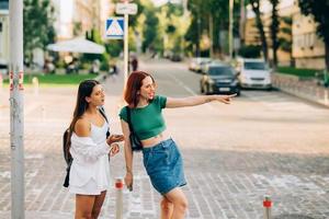 dos amigos turistas consultando una guía en línea en un teléfono inteligente en la calle foto