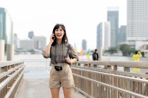 Young Asian woman backpack traveler using mobile phone in express boat pier on Chao Phraya River in Bangkok. photo