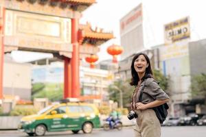 joven asiático mujer mochila viajero disfrutando China pueblo calle comida mercado en bangkok, tailandia viajero comprobación fuera lado calles foto