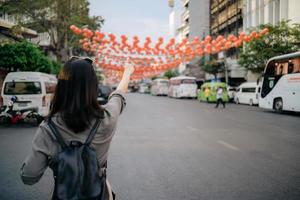 Young Asian woman backpack traveler enjoying China town street food market in Bangkok, Thailand. Traveler checking out side streets. photo