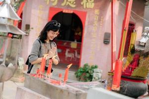 Portrait of asian woman saying prayers and eyes close in front of local Chinese shrine in Bangkok, Thailand photo