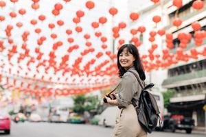 Young Asian woman backpack traveler enjoying China town street food market in Bangkok, Thailand. Traveler checking out side streets. photo